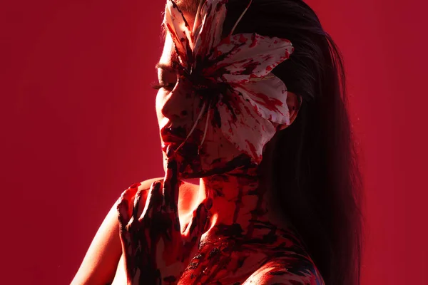 Giglio di sangue, aspetto spaventoso e sexy Halloween. Bella giovane ragazza bruna su sfondo rosso . — Foto Stock