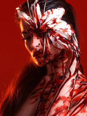 Kanlı Lily, korkunç ve seksi Cadılar Bayramı bakışı. Kırmızı arka planda güzel esmer kız.