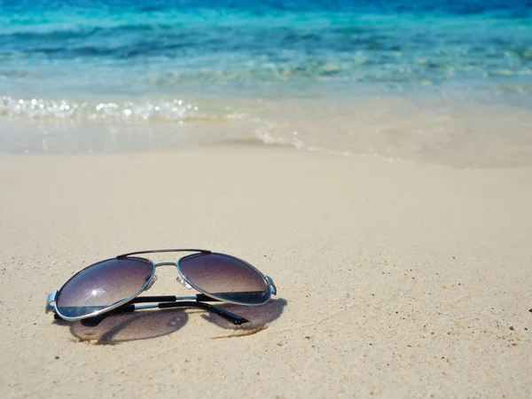 Sluneční brýle na bílém písku na modrém pozadí. Dovolená u teplého moře — Stock fotografie