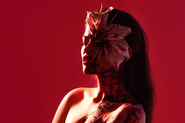 Blood Lily, děsivý a sexy Halloweenský vzhled. Krásná mladá brunetka dívka na červeném pozadí. — Stock fotografie