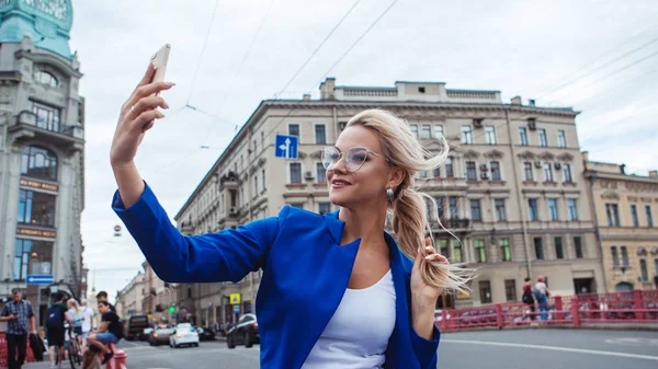 Şık gözlüklü genç kadın selfie çekiyor, tarihi binaların arka planına karşı fotoğraf çekiyor. — Stok fotoğraf