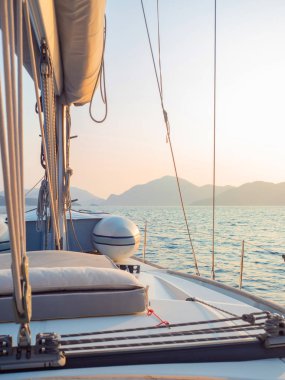 Yelkenli bir yatta tekne gezisi, güvertenin bir parçası ve ufuktaki dağlar, güverteden manzara..