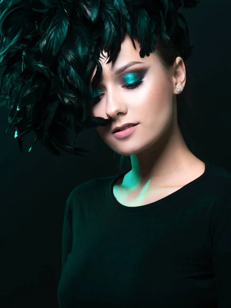 Beautiful young woman in mysterious emerald light. Hat of black feathers, — Stock Photo, Image