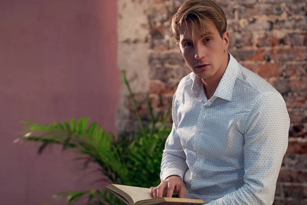 Un joven con una camisa blanca leyendo un libro. Literatura empresarial para el autodesarrollo . — Foto de Stock