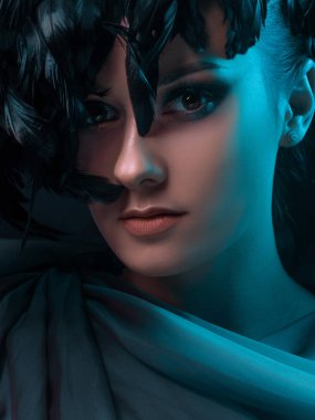 Gizemli zümrüt ışığı altında güzel bir kadın. Siyah tüylü şapka.,