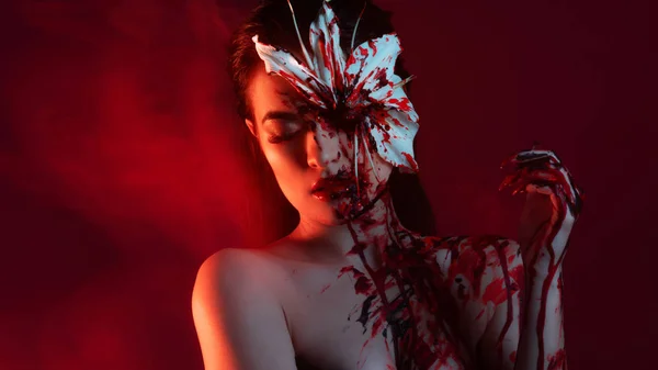 Blood Lily, angstaanjagende en sexy Halloween look. mooi jong brunette meisje op rood achtergrond. — Stockfoto