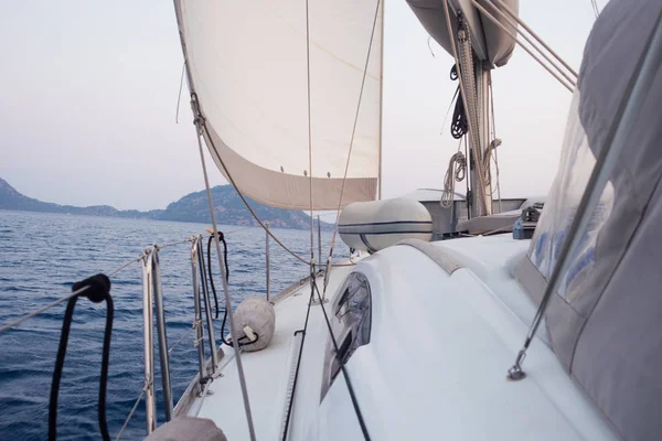 Boat trip on a yacht under sail, a fragment of the deck and the mountains on the horizon, the view from the deck. — Stock Photo, Image