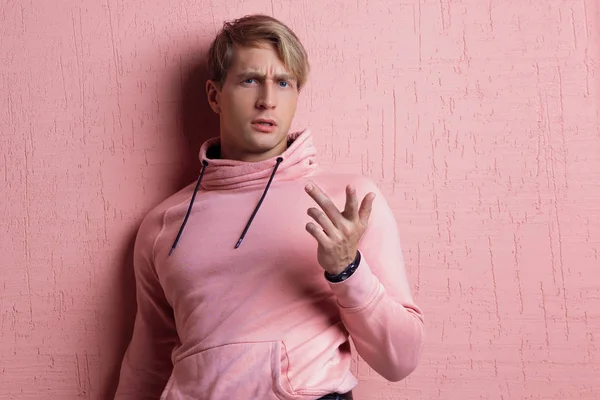 A young man in a pink hoodie on a pink background, portrait of a young stylish guy, — Stock Photo, Image