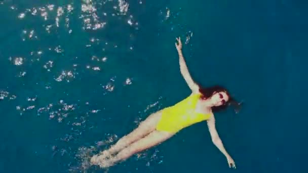Meisje in geel badpak ontspannen en zwemmen in het water — Stockvideo