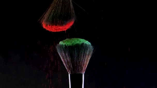 Две мягкие косметические щетки выделяют облако цветного дыма из ярких теней для век и порошка , — стоковое видео