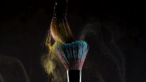 Zwei weiche Kosmetikpinsel setzen eine Wolke aus farbigem Rauch aus hellem Lidschatten und Puder frei, — Stockvideo