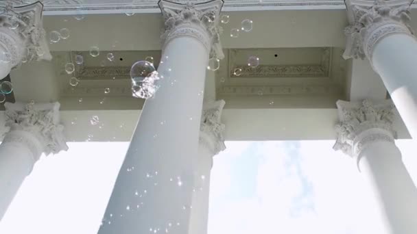 De nombreuses bulles de savon volent sur le fond du portique classique avec des colonnes , — Video