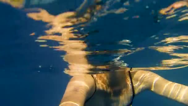 Jonge vrouw in een badpak zwemt in de zee in de buurt van een zeiljacht. — Stockvideo