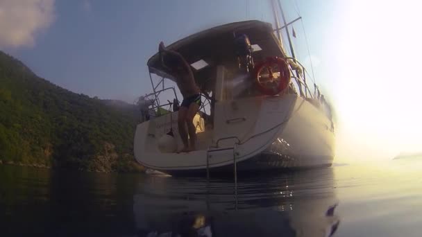 Ragazzi divertenti tuffarsi in mare dal lato di uno yacht a vela. Azione sparatoria da acqua , — Video Stock