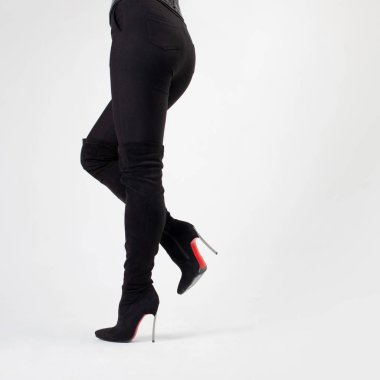 Siyah çizmeler ve pantolonlar içinde ince bacaklar. Yüksek topuklularla yürüyorum. Stiletto ayakkabılar