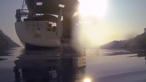 Grappige jongens duiken de zee in vanaf de zijkant van een zeiljacht. Actie vanuit het water, — Stockvideo