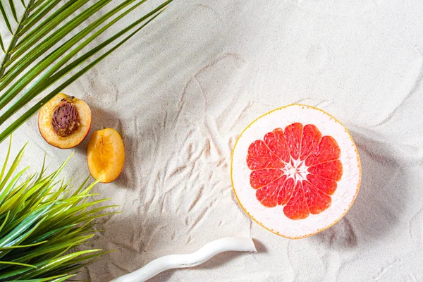 Vacanze al mare. Una foglia di palma, stelle marine, e ramo di albero bianco e frutti succosi si trovano sulla sabbia bianca e fine. Carta da parati desktop. — Foto Stock