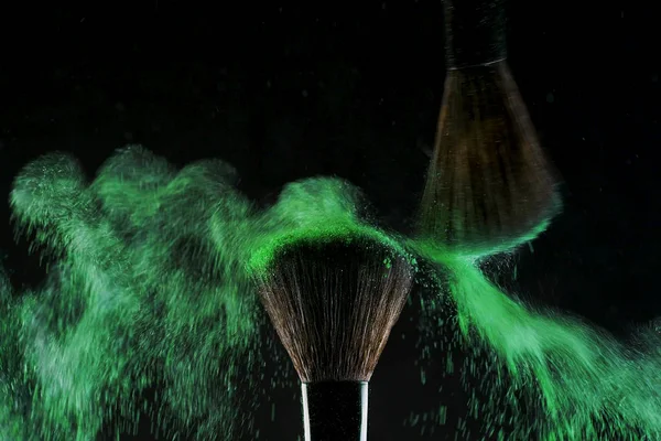 Dos suaves cepillos cosméticos liberan una nube de humo de color verde de sombra de ojos brillante y polvo , — Foto de Stock