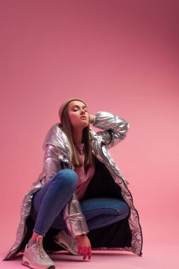 Parlak gümüş rengi ceketli ve örülmüş şapkalı havalı bir kız.,