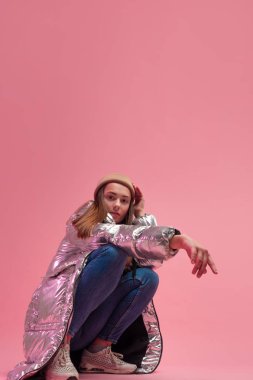 Parlak gümüş rengi ceketli ve örülmüş şapkalı havalı bir kız.,