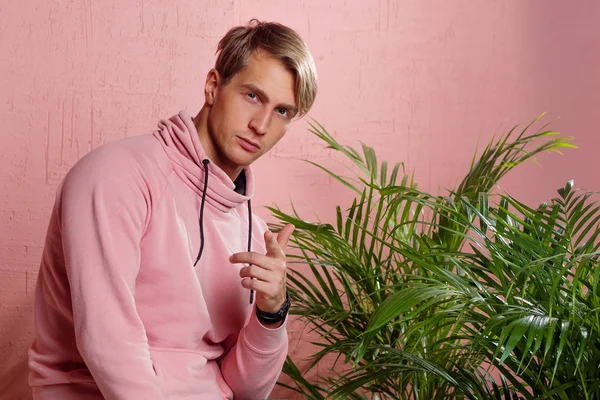 Positive guy in coral hoodie on pink background. Conversation and gestures, — Stock Photo, Image