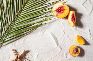 Güzel plaj. Meyveler, denizyıldızları ve palmiye yaprakları beyaz kumlarda yatar..