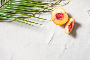 Sahil tatili. Bir palmiye yaprağı ve sulu meyveler beyaz ince kum üzerinde yatıyor. Masaüstü duvar kağıdı.