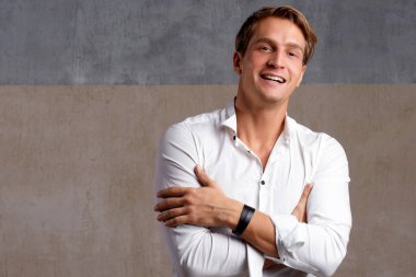 Genç işadamı gülümser ve kameraya bakar. Pozitif ve kendinden emin bir gencin portresi.