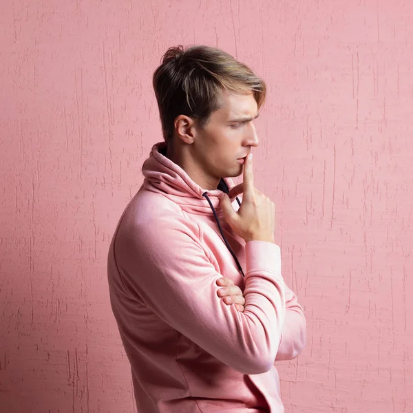Fiatal férfi rózsaszín kapucnis gondol a probléma, egy portré egy srác rózsaszín háttér — Stock Fotó