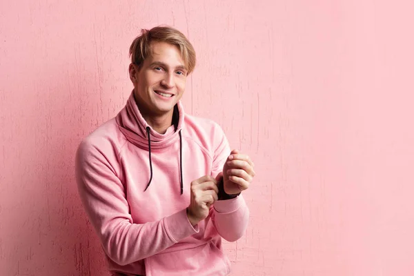 Amable estudiante rubio en sudadera con capucha rosa sobre fondo rosa, espacio de copia . — Foto de Stock