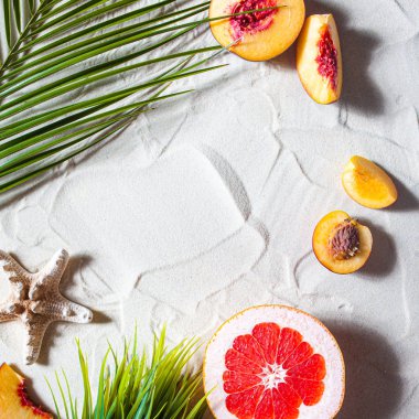 Güzel plaj. Meyveler, denizyıldızları ve palmiye yaprakları beyaz kumlarda yatar..