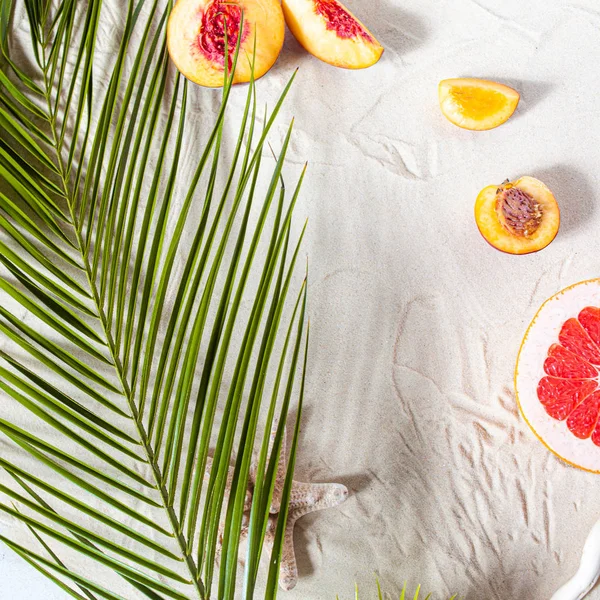 Vacanze al mare. Una foglia di palma, stelle marine, e ramo di albero bianco e frutti succosi si trovano sulla sabbia bianca e fine. Carta da parati desktop. — Foto Stock