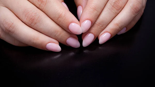 Kvinnors händer med perfekt naken manikyr. Nagellack är en naturlig blekrosa nyans. — Stockfoto