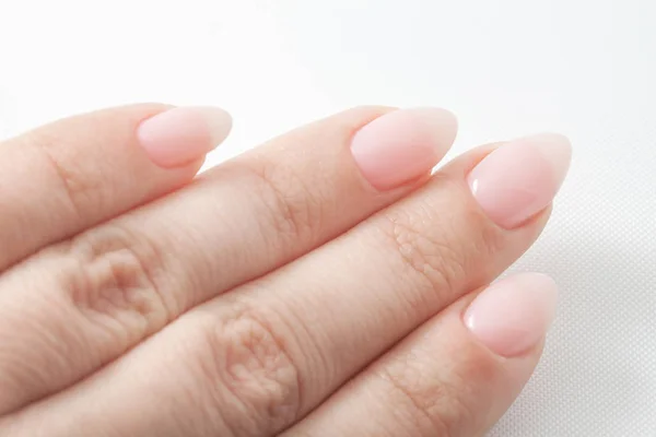 Mãos de mulher com manicure Nude perfeito. Unha polonês é uma sombra rosa pálida natural . — Fotografia de Stock