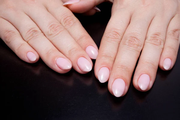 Kobiece dłonie z idealnym manicure nago. Paznokieć polski jest naturalnym jasnoróżowym odcieniem. — Zdjęcie stockowe