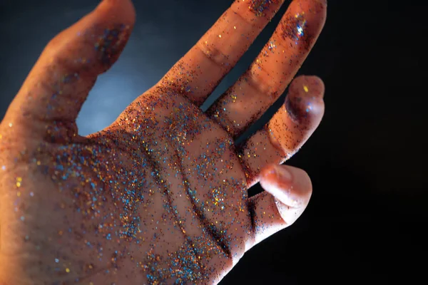 Mano femenina cubierta de lentejuelas. El movimiento de la palma de tu mano y brillo multicolor , — Foto de Stock