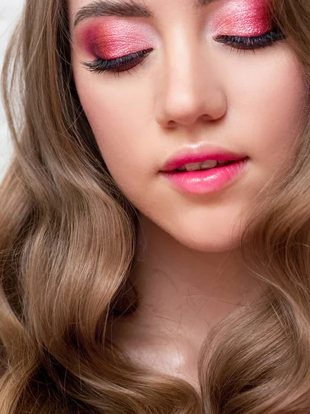 Beautiful young blonde girl in monochrome makeup. Pink lips and eye shadow, delicate makeup.