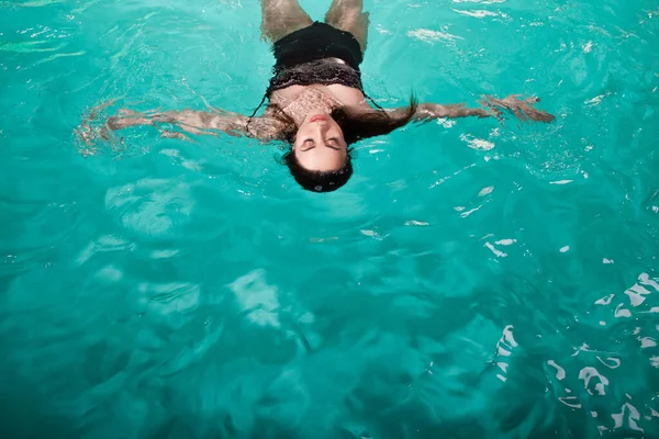 Güzel kız Spa havuzunda dinleniyor, yüzüyor ve rahatlıyor. Genç bir kadın arkada suda yüzüyor., — Stok fotoğraf