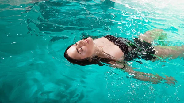 Hermosa chica es relajarse en la piscina del Spa, nadar y relajarse. mujer joven flotando —  Fotos de Stock
