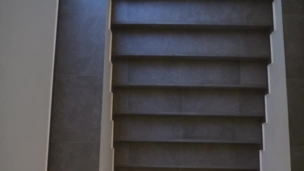 Молодая женщина в стильной деловой одежде идет вверх по лестнице, интерьер бизнес-центра . — стоковое видео