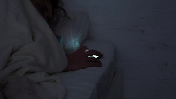 Young man in bed at night uses a smartphone. Social networks and Internet scrolling, — ストック動画