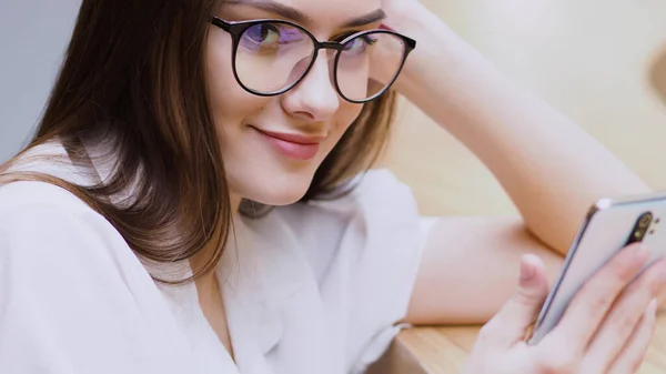 Joven chica morena utiliza un teléfono inteligente para comunicarse. Comunicación en línea en mensajeros , — Foto de Stock