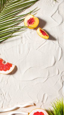 Plaj tatili Bir palmiye yaprağı, denizyıldızı ve beyaz ağaç dalı ve sulu meyveler beyaz kum üzerinde uzanır. Masaüstü duvar kağıdı.