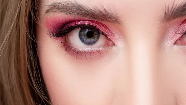 Eye with pink eye shadow and trendy lush eyebrows, trends in makeup.