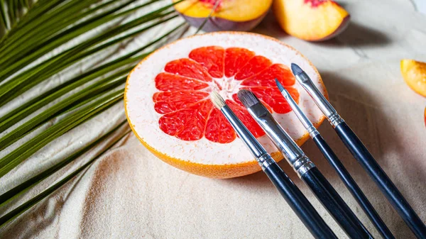 Spiaggia incantevole. Spazzole nero trucco elegante con frutti luminosi, stelle marine, e foglie di palma si trovano sulla sabbia bianca . — Foto Stock