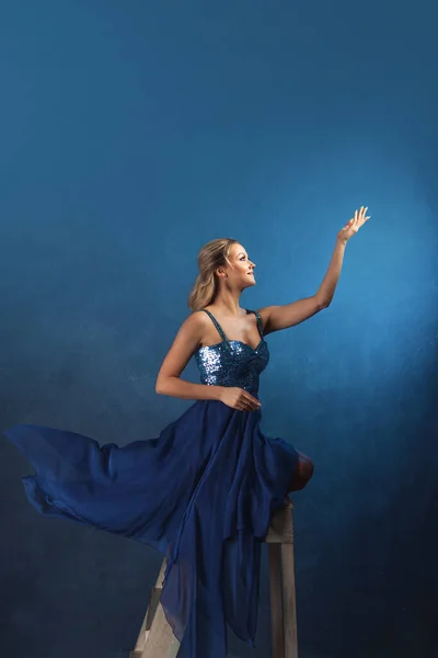 Girl on a stepladder reaches up with her hands, dreaming — Stock Photo, Image