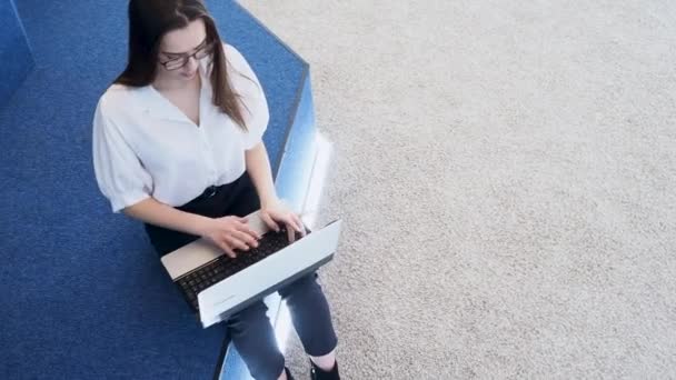 Mladá studentka používá notebook. Mladá brunetka žena sedí a píše na klávesnici, — Stock video