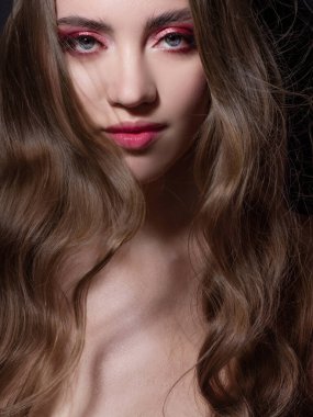 Beautiful young blonde girl in monochrome makeup. Pink lips and eye shadow, delicate makeup.