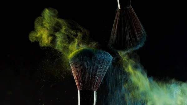 Zwei weiche Kosmetikpinsel setzen eine Wolke aus farbigem Rauch aus hellem Lidschatten und Puder frei, — Stockfoto