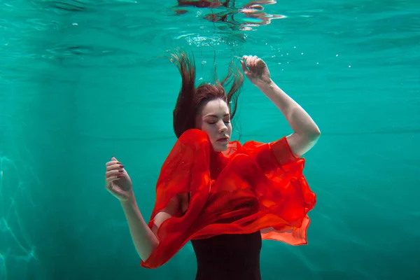 Piękna dziewczyna w czerwonej sukience pływa pod wodą. niesamowite pod wodą — Zdjęcie stockowe